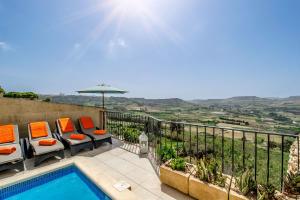 un patio con piscina, sillas y sombrilla en The Blue House Holiday Home, en Għasri