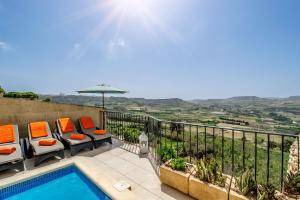 um pátio com uma piscina, cadeiras e um guarda-sol em The Blue House Holiday Home em Għasri