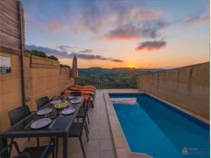 une terrasse avec une table et une piscine dans l'établissement The Blue House Holiday Home, à Għasri
