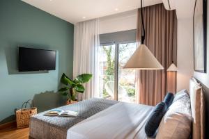 a bedroom with a bed with a tv and a window at Kipos Boutique Suites in Heraklio