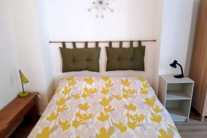 Schlafzimmer mit einem Bett mit gelber und weißer Tagesdecke in der Unterkunft Bilocale nel cuore di Genova in Genua