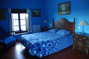 Dormitorio azul con cama y ventana en Posada La Casa Grande, en Jimena de la Frontera