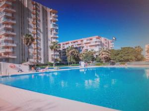 a large blue swimming pool in front of some buildings at Sol y playa in Benalmádena