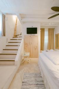 een witte slaapkamer met een bed en een trap bij Romantic Stone House Double room in Kornić