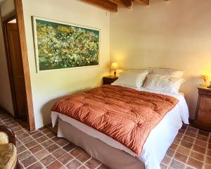 a bedroom with a bed with a painting on the wall at DOMAINE DE LABROUSSE, Maison d'hôtes en Périgord in Agonac