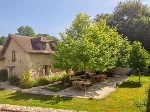 a garden with tables and a tree in front of a house at DOMAINE DE LABROUSSE, Maison d'hôtes en Périgord in Agonac