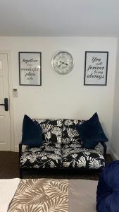 a living room with a couch and a clock on the wall at Bv Homely Studio Fourteen At Deighton Huddersfield in Huddersfield