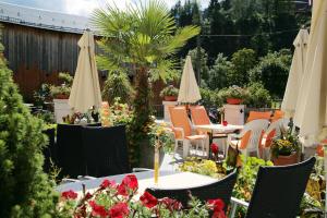 un patio con mesas, sillas y sombrillas en Hotel Eder Michaela, en Saalbach Hinterglemm