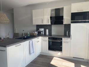 a kitchen with white cabinets and a stove top oven at Schillig, Nordsee - Friesland - Wohnung - neu in Wangerland +11 photos
