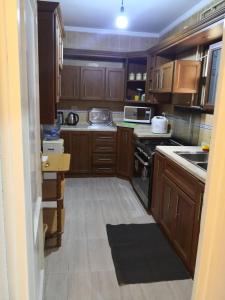 La cuisine est équipée de placards en bois et d'un four avec plaques de cuisson. dans l'établissement Rehab City VIP Full Serviced Apartment الرحاب Guest satisfaction guaranteed, au Caire