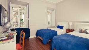 1 dormitorio con 2 camas con sábanas azules y ventana en Bartholomeu Guesthouse, en São Bartolomeu de Messines