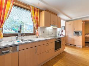kuchnia z drewnianymi szafkami, umywalką i oknem w obiekcie Apartment Wieser by Interhome w mieście Spielbichl