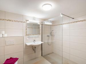 La salle de bains blanche est pourvue d'un lavabo et d'une douche. dans l'établissement Chalet Gnadenalm - OBR103 by Interhome, à Obertauern