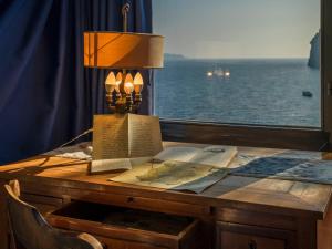 a table with books and a lamp and a window at Apartment Lo Scuopolo-2 by Interhome in Ischia