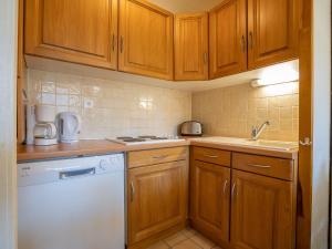 a kitchen with wooden cabinets and a white dishwasher at Apartment Origanes 226 by Interhome in Les Menuires