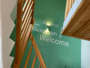 un escalier avec un mur vert et un panneau de bienvenue dans l'établissement Apartment Kühbeck-1 by Interhome, à Bischofsmais