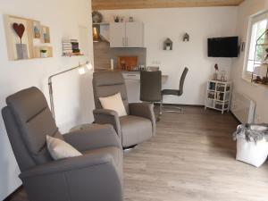 ein Wohnzimmer mit einem Sofa und Stühlen sowie eine Küche in der Unterkunft Holiday Home Caro by Interhome in Kirburg