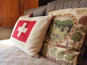 een kussen met een kruis erop zittend op een bank bij Apartment Armorial II - apt 2 by Interhome in Villars-sur-Ollon