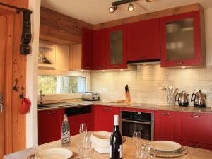 a kitchen with red cabinets and a table with wine glasses at Apartment Armorial II - apt 2 by Interhome in Villars-sur-Ollon +30 photos