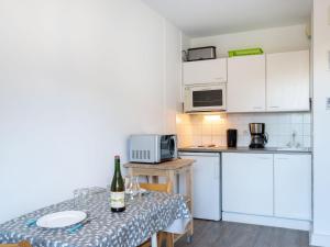 a kitchen with white cabinets and a table with a bottle of wine at Apartment Fleur Marine-16 by Interhome in Cabourg
