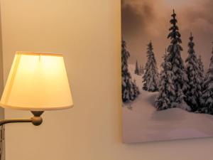 een lamp naast een schilderij van met sneeuw bedekte bomen bij Apartment Les Girolles B15 by Interhome in Villars-sur-Ollon