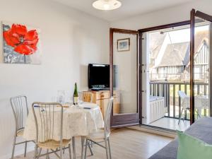 una sala da pranzo con tavolo, sedie e TV di Apartment Fleur Marine-9 by Interhome a Cabourg