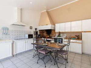 eine Küche mit weißen Schränken und einem Tisch mit Stühlen in der Unterkunft Holiday Home Les Amandiers - MZN100 by Interhome in Mazan