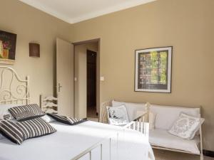 ein Schlafzimmer mit einem weißen Bett und einem Sofa in der Unterkunft Holiday Home Le Cèdre - MBE101 by Interhome in Ménerbes