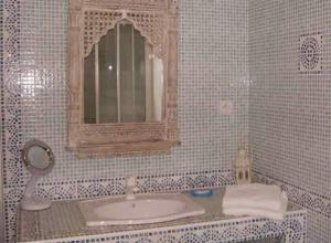 Baño de azulejos blancos con lavabo y espejo en La Villa Florida, en Dieppe