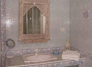 Baño de azulejos blancos con lavabo y espejo en La Villa Florida en Dieppe