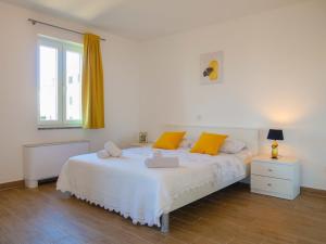 a bedroom with a white bed with yellow pillows and a window at Apartment Marija - VRB100 by Interhome in Vrbnik