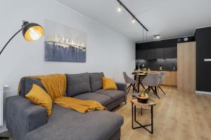 a living room with a gray couch and a kitchen at Lux Wellness Resort & SPA Apartments by the River by Renters Prestige in Dziwnów