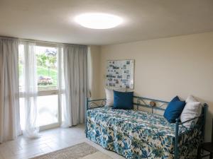 a bedroom with a bed with blue pillows and a window at Apartment Ca' Marianna by Interhome in Roatto