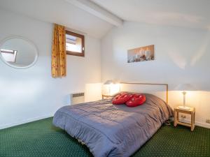 a bedroom with a bed with two red pillows on it at Apartment Nécou-1 by Interhome in Les Menuires