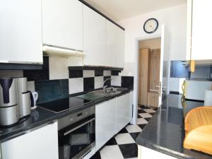 eine Küche mit weißen Schränken und einer Uhr an der Wand in der Unterkunft Apartment Nina by Interhome in Mimice