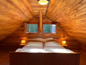 グライフェンブルクにあるChalet Wassertheureralm by Interhomeのランプ2つと窓2つが備わる木造の部屋のベッド1台分です。