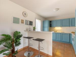 a kitchen with blue cabinets and stools at Holiday Home Le Mas d'Esquières 7 by Interhome in Les Issambres