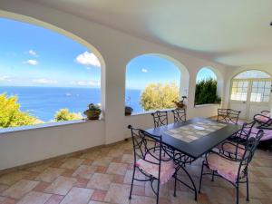 ein Esszimmer mit Tisch und Stühlen und dem Meer in der Unterkunft Holiday Home Fontanarosa by Interhome in SantʼAgata sui Due Golfi