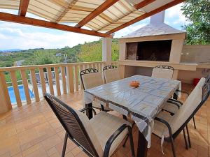 a table and chairs on a deck with a fireplace at Holiday Home Villa Tonka by Interhome in Sutivan +9 photos