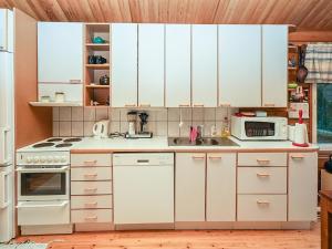 eine Küche mit weißen Schränken und einem Herd mit Backofen in der Unterkunft Holiday Home Saapunkijärvi- pitkäperä by Interhome in Saapunki + 15 Fotos