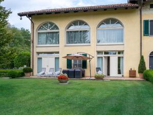 una casa con dos sillas y un paraguas en un patio en Holiday Home Villa Carlotta by Interhome, en Costigliole dʼAsti