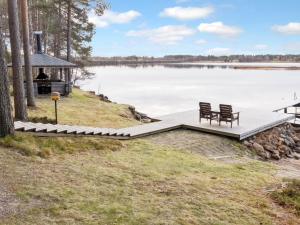 a dock on a lake with two chairs and a gazebo at Holiday Home Järvelä by Interhome in Kemijärvi