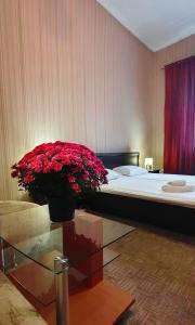 a bedroom with a bed with a vase of red flowers at Apart-Hotel City Center Contrabas in Lviv