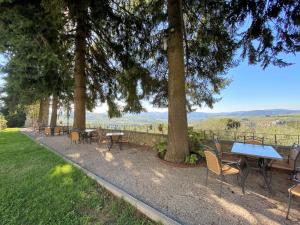 una fila di tavoli e sedie seduti sotto gli alberi di Apartment Villa Grassina-1 by Interhome a Pelago