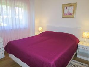 ein Schlafzimmer mit einem Bett mit einer lila Decke in der Unterkunft Holiday Home Ive by Interhome in Petrcane