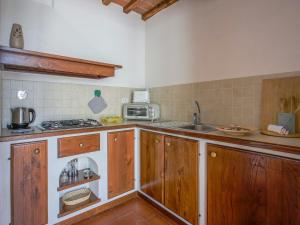 eine Küche mit Holzschränken, einer Spüle und einer Mikrowelle in der Unterkunft Holiday Home Castiglioni-1 by Interhome in Castiglione