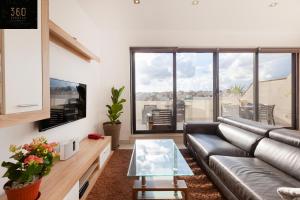 ein Wohnzimmer mit einem Ledersofa und einem TV in der Unterkunft Penthouse with BBQ Kitchen Island & Massive Living room by 360 Estates in St Julian's