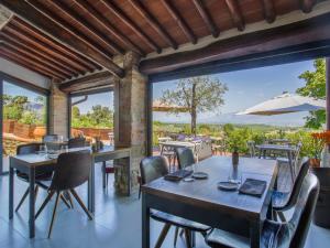 Un comedor con mesas y sillas y grandes ventanales. en Apartment Le Poggiole-2 by Interhome, en Cavriglia