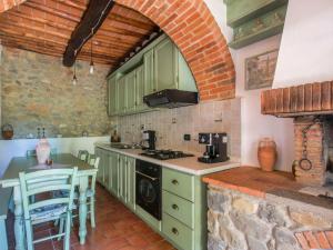 una cucina con armadi verdi e un muro di mattoni di Apartment Le Poggiole-2 by Interhome a Cavriglia