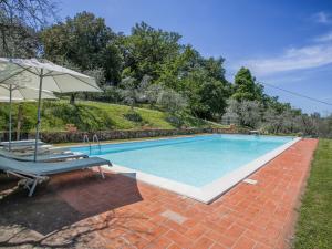 a swimming pool with two chairs and an umbrella at Holiday Home Le Poggiole-1 by Interhome in Cavriglia